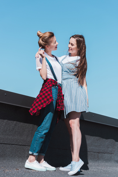 low angle view of two stylish female friends standing at rooftop  - Foto, immagini