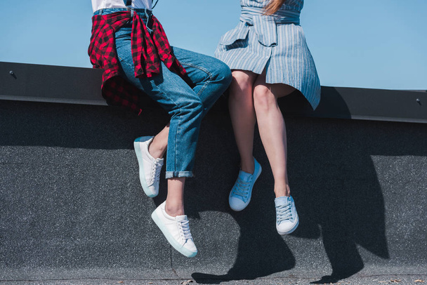 cropped image of two stylish female friends sitting at rooftop  - Fotoğraf, Görsel