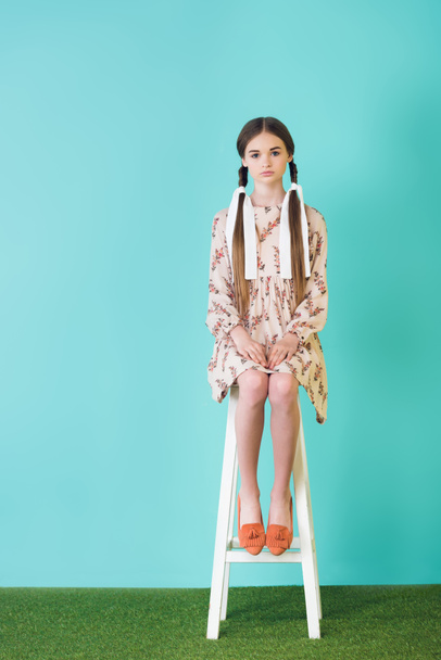 stylish teen girl in summer dress with braids sitting on stool, on turquoise - 写真・画像