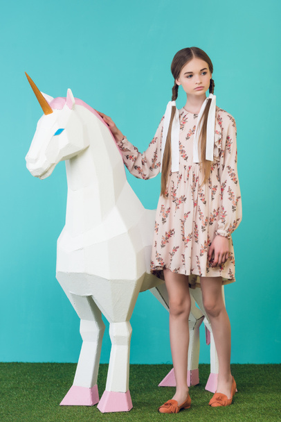 fashionable youth girl posing with big white unicorn on turquoise - Foto, Imagen