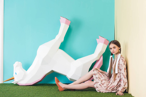beautiful elegant teen girl posing with big unicorn upside down, on blue - Photo, Image