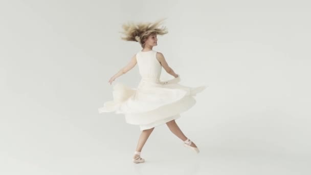 käsite kauneus, tuoreus ja nuoruus. Ballerina pyörii vaaleassa lentävässä mekossa valkoisella taustalla. hidastettuna
 - Materiaali, video