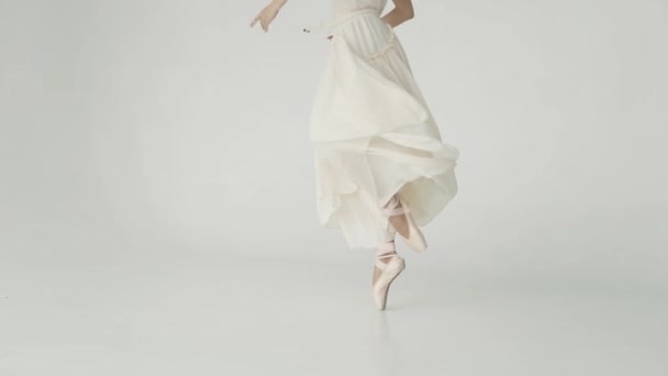 Detail nohy baletka. baletka se točí ve světle létající šaty na bílém pozadí. Zpomalený pohyb - Záběry, video