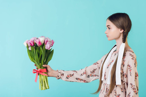 fiatal lány védőrácsok, gazdaság csokor tulipán, elszigetelt türkiz nyári ruha - Fotó, kép