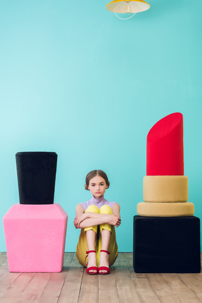 beautiful stylish girl sitting between big nail polish and lipstick  - Фото, изображение