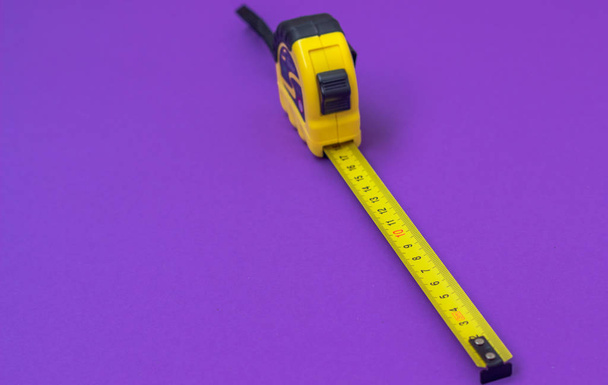 Żółty budowlane Ruletka na fioletowym tle - Zdjęcie, obraz