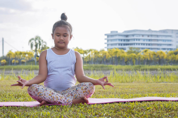 Dívčí praktikující jógu v parku slouží k posílení koncentrace a zdraví, jóga pro děti bavit meditace aktivity pro děti - Fotografie, Obrázek