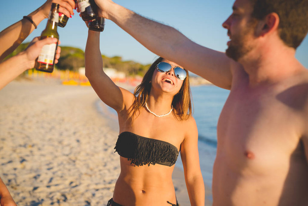 Gruppo di amici millennials in spiaggia facendo brindisi
  - Foto, immagini