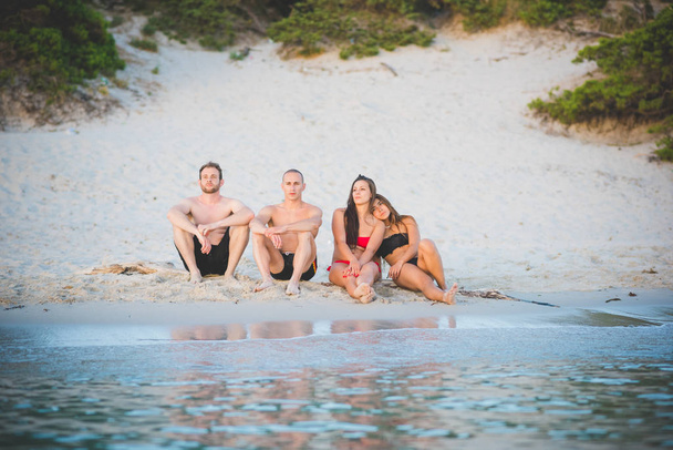 Gruppe von Freunden Millennials in Badeanzügen sitzen am Strand im Freien und betrachten die Aussicht  - Foto, Bild