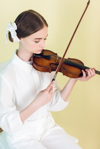 teen musician in white outfit playing violin, isolated on yellow - Photo, Image