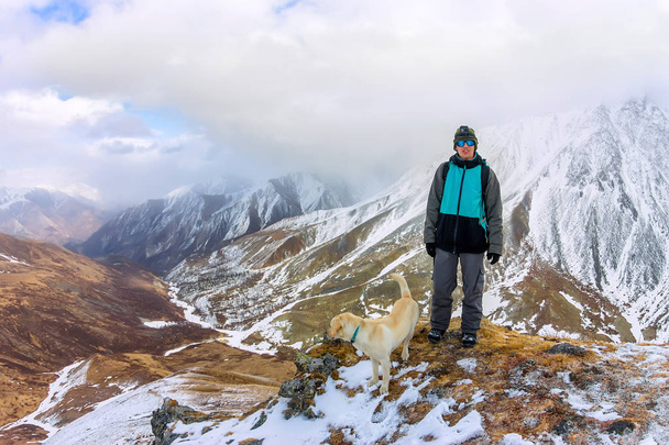 Man and dog labrador hike the cloudy mountains. - Photo, Image