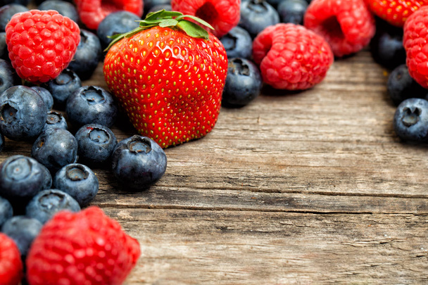 Summer Berries Border Background. Strawberry, raspberry and blueberries on wooden table - Photo, Image