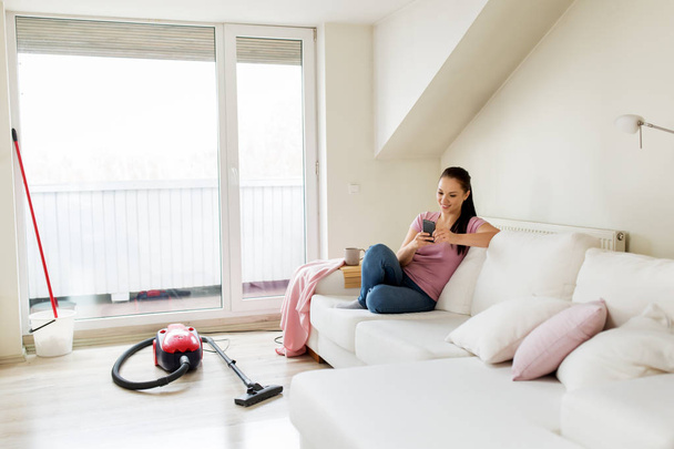 woman with smartphone and vacuum cleaner at home - Fotoğraf, Görsel
