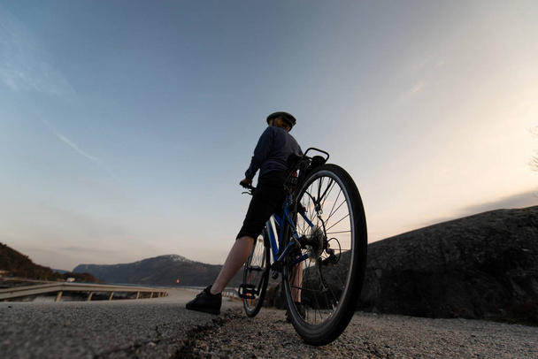 Χαμηλή γωνία θέα του ποδηλάτη με την Ανατολή του ηλίου. Αθλητισμός και ενεργό ζωή έννοια κατά τη θερινή ώρα. - Φωτογραφία, εικόνα