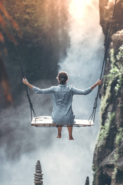 Beautiful woman swings near waterfall in the jungle of Bali island, Indonesia. - 写真・画像