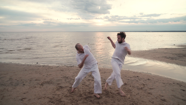 Двоє чоловіків практикують капоейру на пляжі
 - Кадри, відео