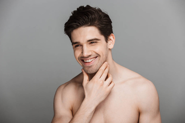 Beauty portrait of half naked laughing young man looking away isolated over gray background - Foto, Imagem