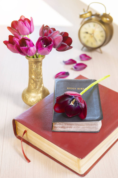 Szent Biblia, és fából készült asztal háttér virágokkal régi arany ébresztőóra - Fotó, kép