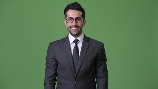 Νέος όμορφος γενειοφόρος Περσικά επιχειρηματίας ενάντια σε πράσινο φόντο - Πλάνα, βίντεο