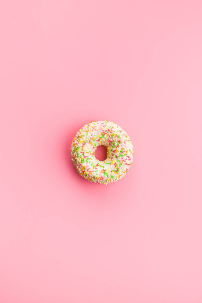 Sweet sprinkled donut on pink background. - Foto, afbeelding