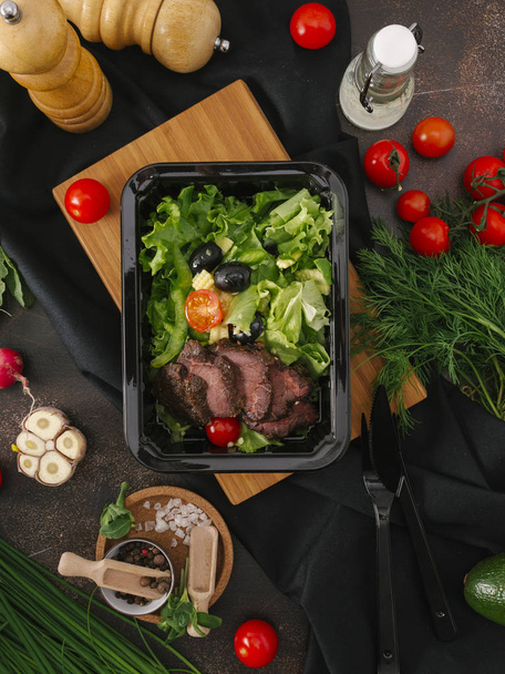 Nahrungsmittelzusammensetzung aus gebackenen Fleischscheiben in schwarzer Schale mit Gemüse - Foto, Bild