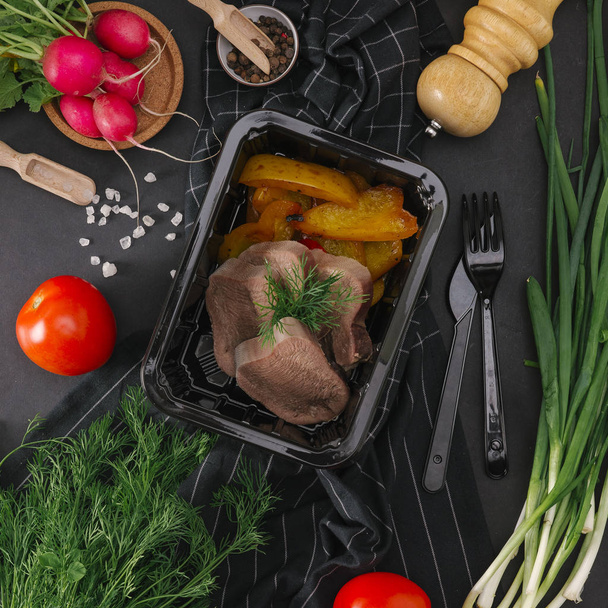 Composizione alimentare di lingua bollita con peperoni al forno in vassoio nero
 - Foto, immagini