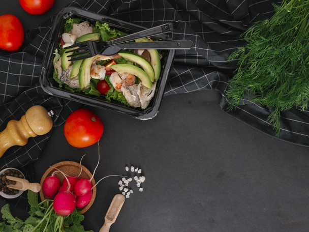Composición alimenticia de ensalada con pescado, camarones, calamares, aguacate, tomates y lechuga en bandeja negra
 - Foto, Imagen