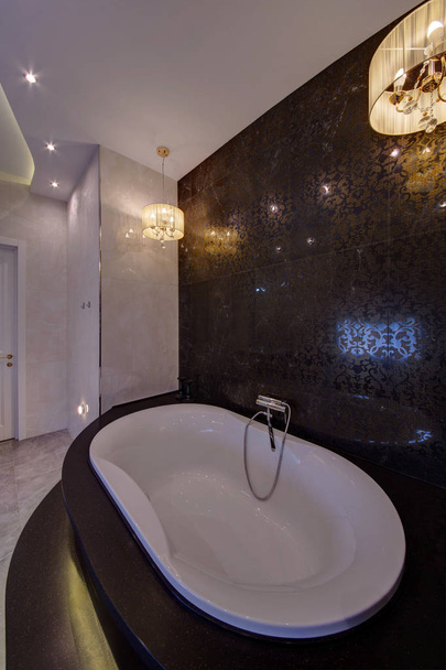 A white jacuzzi on a dark tiled wall with the crane - Foto, Imagen