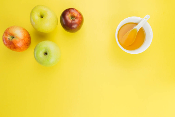 Рош ха-Шана, яблоки и чашка меда на желтом фоне. свободное место для текста
 - Фото, изображение