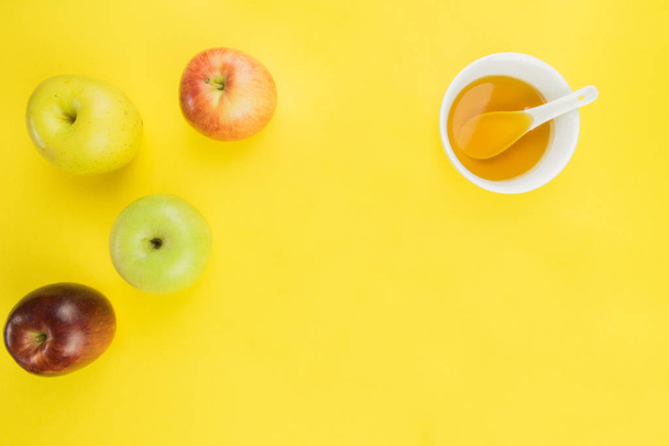 Rosh Hashaná, manzanas y taza de miel sobre fondo amarillo. espacio libre para texto
 - Foto, Imagen