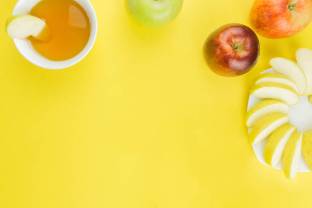 Рош ха-Шана, яблоки и чашка меда на желтом фоне. Нарезанные яблоки на тарелке. свободное место для текста
 - Фото, изображение