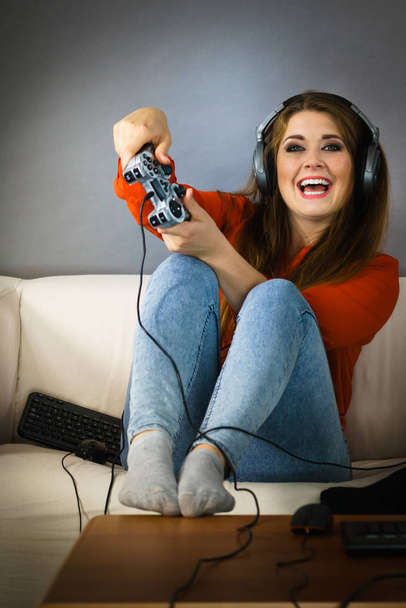 Nerd geek young adult women playing on the video console holding game pad sitting on sofa. Gaming gamers concept. - Фото, изображение