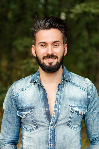 smiling handsome bearded man wearing trendy denim shirt outdoor - Fotografie, Obrázek