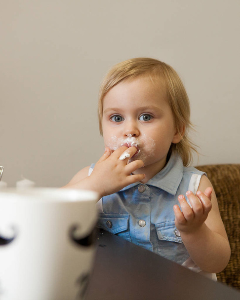 little girl eats an acrele in the kitchen. - Foto, Imagen
