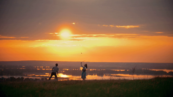 Девушка и парень играют в бадминтон на поле, стоят рядом со своим маленьким сыном, закатный летний вечер
 - Кадры, видео