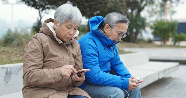 Senior couple using cellphones together at street  - Photo, Image