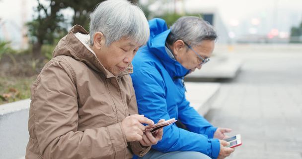 Παλιά ζευγάρι χρησιμοποιώντας τα κινητά τηλέφωνα στην πόλη μαζί  - Φωτογραφία, εικόνα
