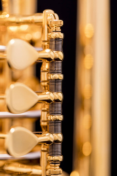 Een deel van een goud vergulde roterende trompet op een zwarte achtergrond - Foto, afbeelding