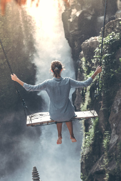 Beautiful woman swings near waterfall in the jungle of Bali island, Indonesia. - Photo, image