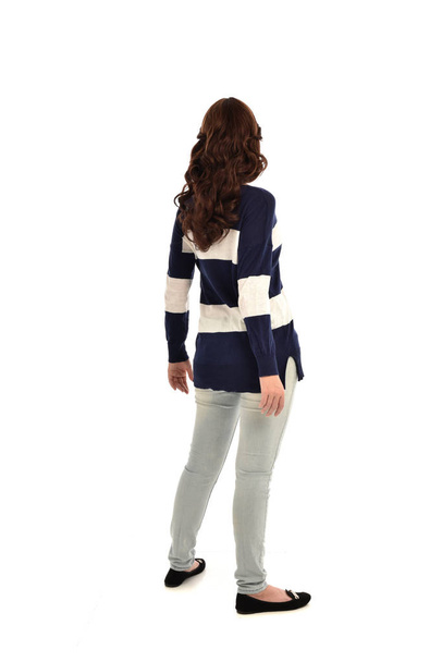 полноразмерный портрет девушки в джинсах и свитере. Стоя поза, изолированные на белом фоне студии
. - Фото, изображение