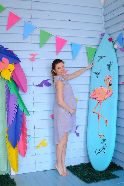 Jovem grávida de pé perto de prancha de surf e decorado casa de crianças
. - Foto, Imagem