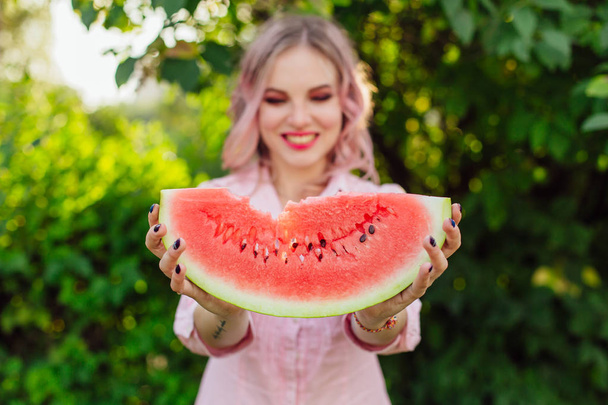 Beautiful smiling young woman with pink hair holding sweet juicy watermelon in hands - Fotografie, Obrázek