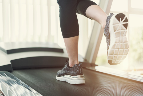 Healthy and fitness concept. Sport people running on treadmill at gym in the morning with sunlight. Close up of shoes shot with free copy space background. - Photo, Image