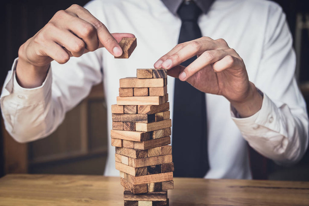 Images of hand of businesspeople placing and pulling wood block on the tower, Alternative risk concept, plan and strategy in business, Risk To Make Business Growth Concept With Wooden Blocks. - Фото, зображення