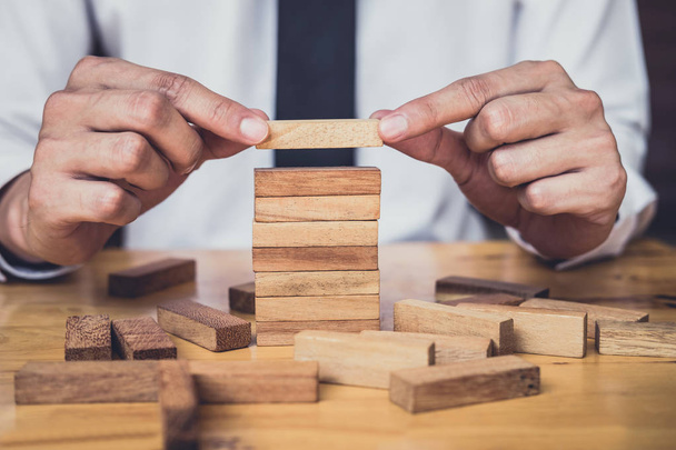 Risk To Make Business Growth Concept With Wooden Blocks, hand of man has piling up and stacking a wooden block, Alternative risk concept, plan and strategy in business. - Fotoğraf, Görsel