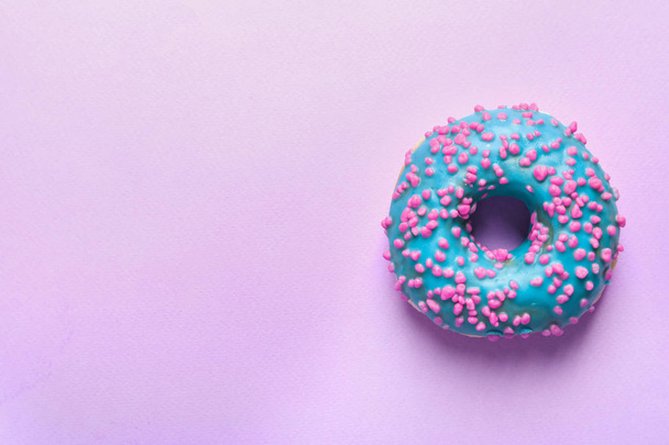 Delicious glazed doughnut with sprinkles on color background, top view - Foto, imagen