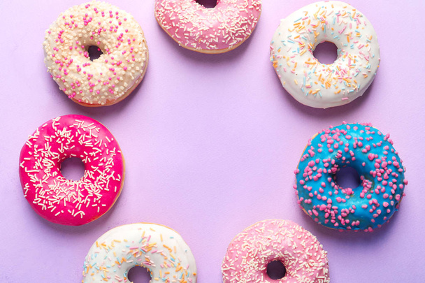 Frame made of delicious doughnuts on color background, top view - Foto, immagini