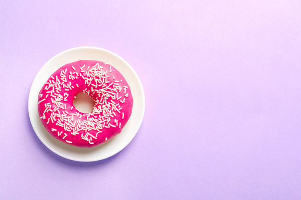 Plate with delicious doughnut on color background, top view - Foto, afbeelding