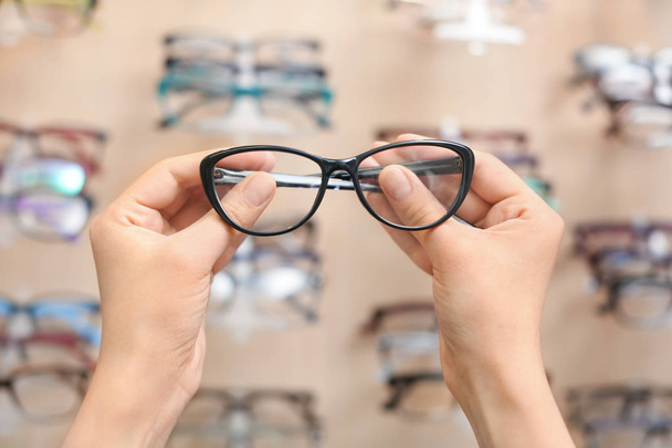 Female ophthalmologist with glasses near showcase in optical store - Foto, Bild