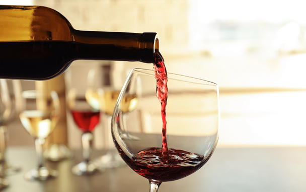 Gieten van heerlijke rode wijn in glazen op tafel - Foto, afbeelding